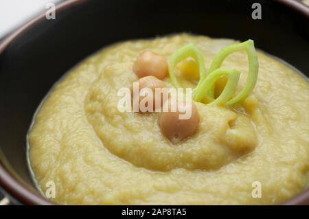 Creme aus Lauch und Kichererbsen in einer schwarzen runden Schüssel, Nahaufnahme Stockfoto