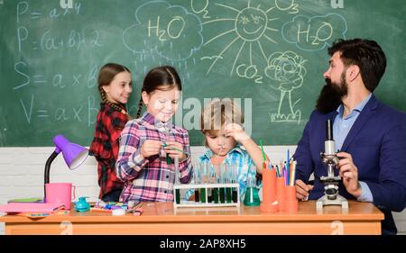 Wissenschaft ist immer die Lösung. Reaktion beobachten. Experiment der Schulchemie. Erklären der Chemie für Kinder. Faszinierende Chemiestunde. Mann bärtige Lehrer und Schüler mit Reagenzgläsern im Klassenzimmer. Stockfoto