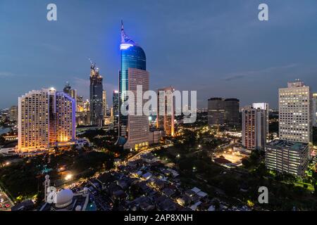 Atemberaubende Dämmerung über der Innenstadt von Jakarta, die mit niedrigen Häusern in der Hauptstadt Indonesiens kontrastieren Stockfoto