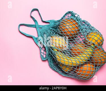 Einkaufstasche aus Mesh mit Bio-Früchten auf pastellrosa Hintergrund. Flache Lage, Draufsicht. Kein Abfall, Kunststofffreies Konzept. Gesunde, saubere Ernährung und d Stockfoto