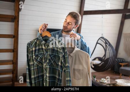 Gutaussehender Mann, der ein Hemd zum tragen wählt Stockfoto