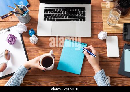 Frau schreiben in Notizbuch mit Stift am Schreibtisch Stockfoto