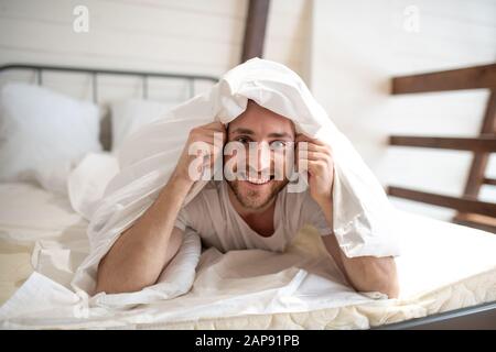 Junger bärtiger Mann, der seinen Kopf mit Decke bedeckt Stockfoto