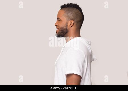 Lächelnd schwarzer Mann stehen im Profil im Studio isoliert Stockfoto