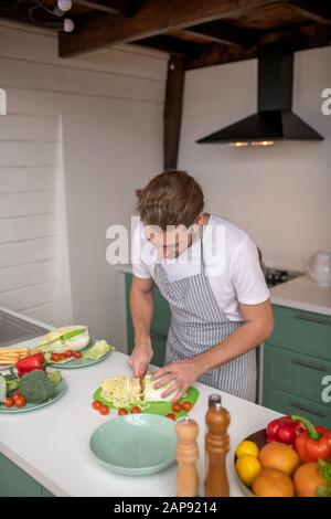 Männlichen Garen Sie minuziös Gemüse für Salat Stockfoto