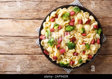 Servieren von orecchiette Pasta mit Brokkoli und gebratenen italienischen Würstchen in einem Teller auf dem Tisch. Horizontale Draufsicht von oben Stockfoto