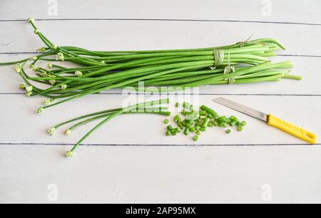 Haufen Frühlingszwiebeln mit Blumenköpfen auf schwarzem Grund. Blühende Zwiebelblüten. Frühlingszwiebel mit Blumenkopf. Allium neapolitanum closeup. Stockfoto