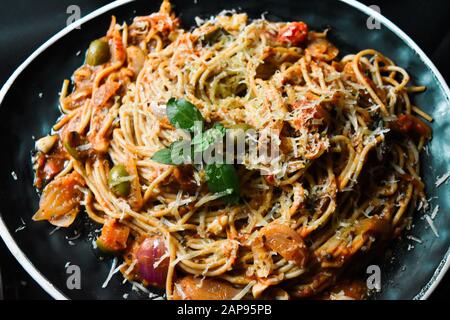 Klassische italienische Spaghetti Bolognese Sauce Pasta in schwarzem Gericht, gehäufte Spaghetti bolognese Pasta Closeup mit Zutaten zum Kochen von Pasta und Nudelgericht Stockfoto