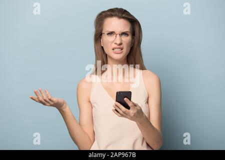 Verwirrt Frau in Gläser halten Handys in Verbindung Probleme Stockfoto