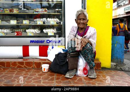 Antipolo City, Philippinen - 18. Januar 2020: Die alte philippinische Frau sitzt auf einem Bürgersteig und bittet die Menschen, ihr Essen oder Almosen zu geben. Stockfoto