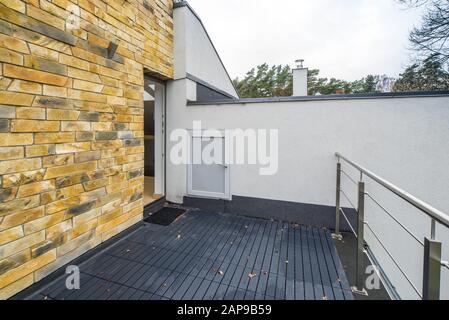 Blick auf die Straße von der Terrasse eines Privathauses. Metallgeländer. Mauer aus Backstein. Weiße Wand. Stockfoto