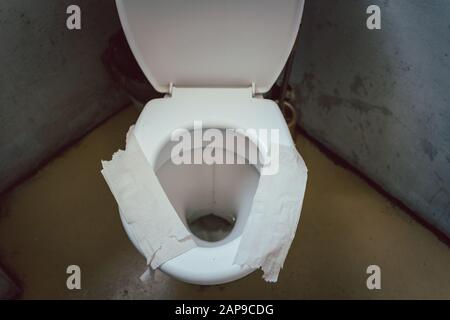 Schmutziger, mit toilettenpapier bedeckter wc-Sitz als Sitzisolierung Stockfoto