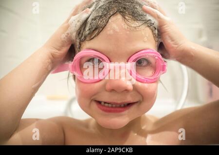 4 Jahre Junge tragen eine Schutzbrille an der Badewanne. Keine Augen mehr, die das Haar-Waschkonzept aufstechen Stockfoto