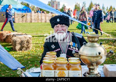 Izmailovsky Park, Moskau, Russland-1. Oktober 2016: Nachfahren von Kosaken bei der Messe- und Kosakensammlung. Ein alter Kosak verkauft Honig und Kräutertee Stockfoto