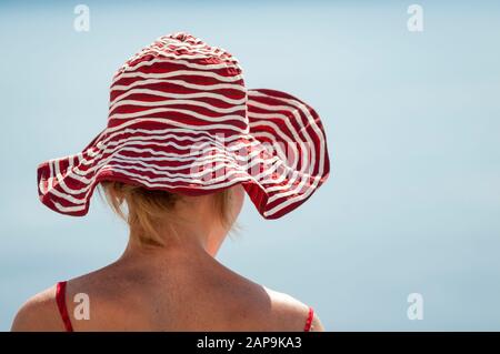 Blick auf den Sonnenhut, der unerkennbare junge Frau beschattete, die in den sonnigen blauen Himmel blickt Stockfoto