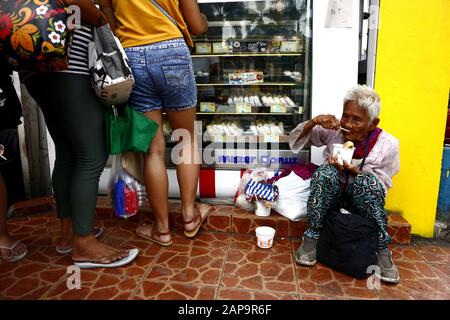 Antipolo City, Philippinen - 18. Januar 2020: Die alte philippinische Frau sitzt auf einem Bürgersteig und bittet die Menschen, ihr Essen oder Almosen zu geben. Stockfoto