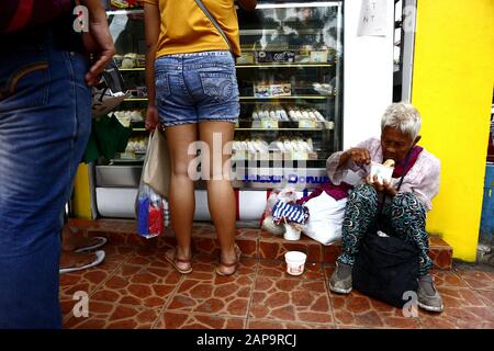 Antipolo City, Philippinen - 18. Januar 2020: Die alte philippinische Frau sitzt auf einem Bürgersteig und bittet die Menschen, ihr Essen oder Almosen zu geben. Stockfoto