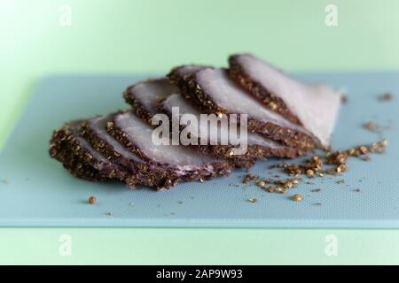 Geschnittenem gekochtem Schweinefleisch auf einem blauen Schneidbrett auf einer Münze Hintergrund. Eine Zutat für eine ketogenic Diät. Kohlenhydratarme, fettreiche. Stockfoto