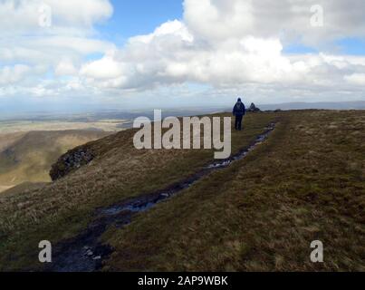 Einsamer Mann, Der Auf dem Gipfel des Wainwright 'Bannerdale Crags' in Mosedale, Lake District National Park, Cumbria zum Cairn Pile of Stones läuft. Stockfoto