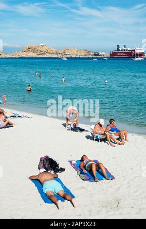 Ile-ROUSSE, FRANKREICH - 22. SEPTEMBER 2018: Am Strand sonnen sich Menschen in Ile-Rousse, Korsika, Frankreich, und auf der Insel Ile de la Pietra und ein Schiff auf Stockfoto