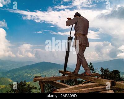 Örtlicher Arbeiter schneide Holzstämme für den Hausbau in der Region Helambu Stockfoto