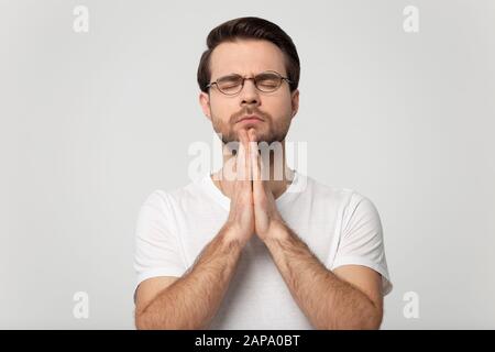 Kopf schoss betenden Mann isoliert auf grauem Studio-Hintergrundporträt. Stockfoto