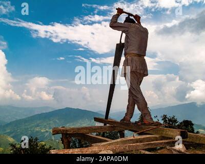 Örtlicher Arbeiter schneide Holzstämme für den Hausbau in der Region Helambu Stockfoto