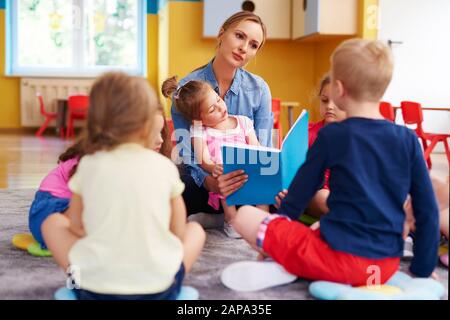 Vorschullehrer liest gerade ein Buch Stockfoto