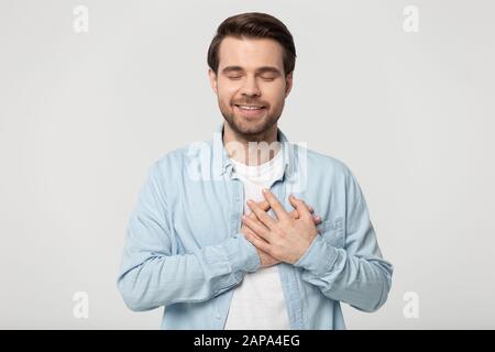 Kopfschuss Portrait junger Mann, der gekreuzte Hände auf der Brust falten kann. Stockfoto