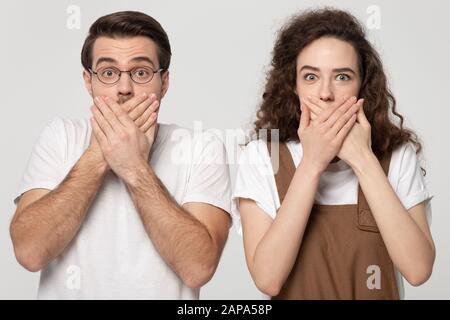 Überrascht schockierte ein tausendjähriges Paar, das die Münder mit den Händen bedeckt. Stockfoto