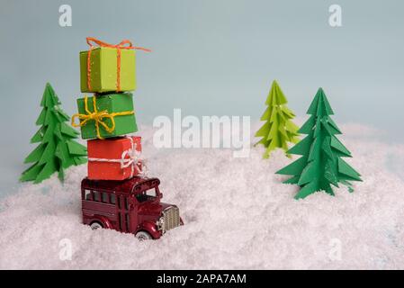 Ein spielzeugauto trägt Geschenke unter dem Weihnachtsbaum im Schnee. Blick von oben. Kopieren Sie Platz Stockfoto