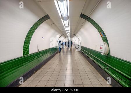 Einige Pendler im weißen Tunnel der U-Bahn-Station in London, Großbritannien Stockfoto
