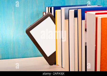 Zwischen einer Reihe von gedruckten Büchern wird ein E-Book-Reader eingefügt Stockfoto