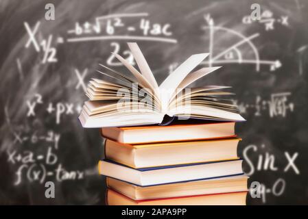 Buch auf einem Stapel vor einer Tafel mit mathematischen Formeln geöffnet Stockfoto
