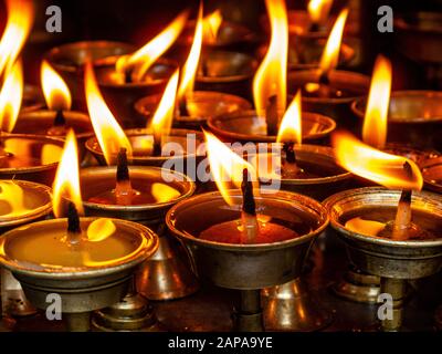 Die flackernden Flammen der tibetischen Butterlampen in einem Tempel Stockfoto