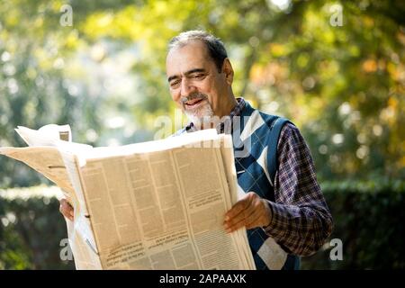 Leitender Mann liest Zeitung im Park Stockfoto
