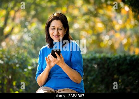 Glückliche Seniorin Textnachrichten per Handy Stockfoto