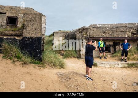 Touristen, die Fotos von einem alten deutschen Weltkriegsbunker am Utah Beach, Normandie, Frankreich machen Stockfoto