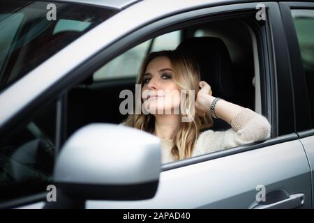 Schöne blonde Frau, die im Auto auf einem Fahrersitz sitzt Stockfoto