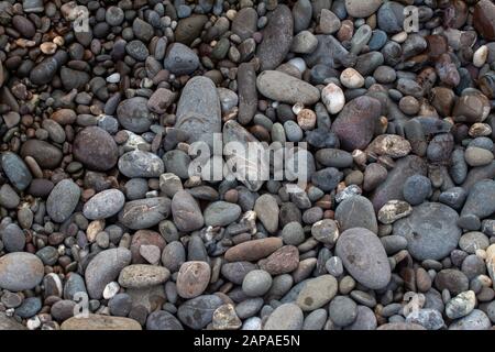 Meer Kieselsteinen farbige Granit am Strand Hintergrund Steine. Der Strand mit Sand und Steine von den Wellen des Meeres umspült. Stockfoto