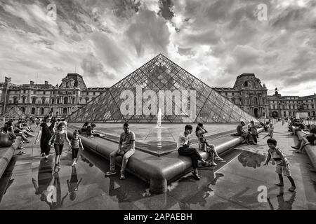 Leute, die an den Springbrunnen vor dem Louvre sitzen Stockfoto