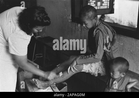 Rotkreuz-Aktivität [Semarang] Beschreibung: Die Beine eines Jungen werden von einem Mitarbeiter des Roten Kreuzes betreut Datum: Juli 1947 Standort: Indonesien, Java, Niederländisch-Indien Stockfoto