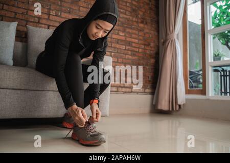 Junge muslimische Frauen in asien tragen Sporthijabs und fixieren Schnürsenkel vor der Tür Stockfoto