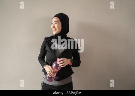 Hijab sportliche asiatische Damen, die Sportswear tragen, halten eine Flasche Stockfoto