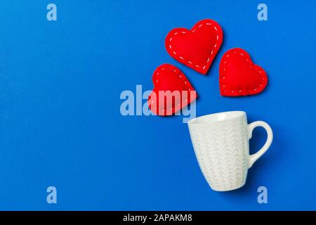 Draufsicht Komposition von roten Herzen, die aus einer Tasse auf farbenfrohem Hintergrund mit Kopierraum herausfallen. Romantisches Beziehungskonzept. St. Valentinstag. Stockfoto