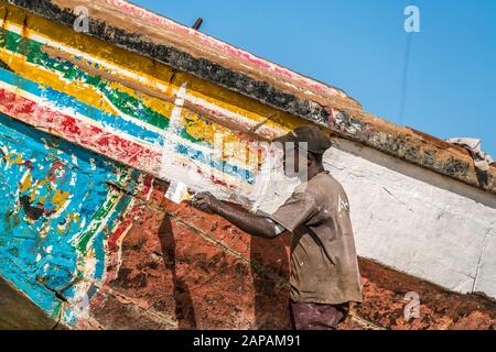 Fischer beim bemalen eines bunten Fischerboots, Tanji, Gambia, Westafrika, man Painting a bunt Fishing Boat, Tanji, Gambia, Westafrika, Stockfoto