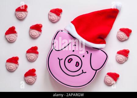 Percy Pigs Zinn von Keksen, die Santa Hut mit M&S Percy Pig Fröhliche Weihnachtsbonbons mit echtem Fruchtsaft tragen, isoliert auf weißem Hintergrund Stockfoto