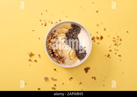 Gesunde Smoothie-Schüssel mit Kokosnuss, Bananen, Chia-Samen, Sesamsamen und Granola. Über der Szene auf hellem Hintergrund. Stockfoto