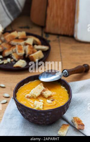 Gemüsesuppenpüree aus Kürbis, Karotten und Sellerie, serviert mit Croutons und Kürbiskernen. Rustikaler Stil. Stockfoto