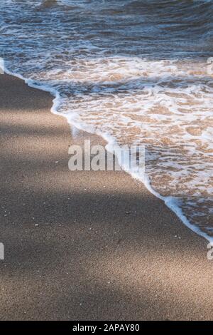 Hintergrund der Natur. Strandszene mit Meereswellen und Sand. Licht und Schatten Stockfoto